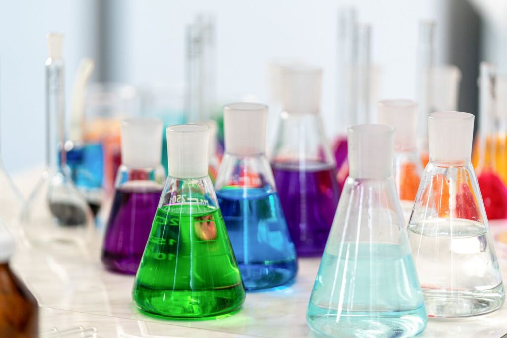 Close-up of colorful chemical solutions in glass beakers in a laboratory setting.